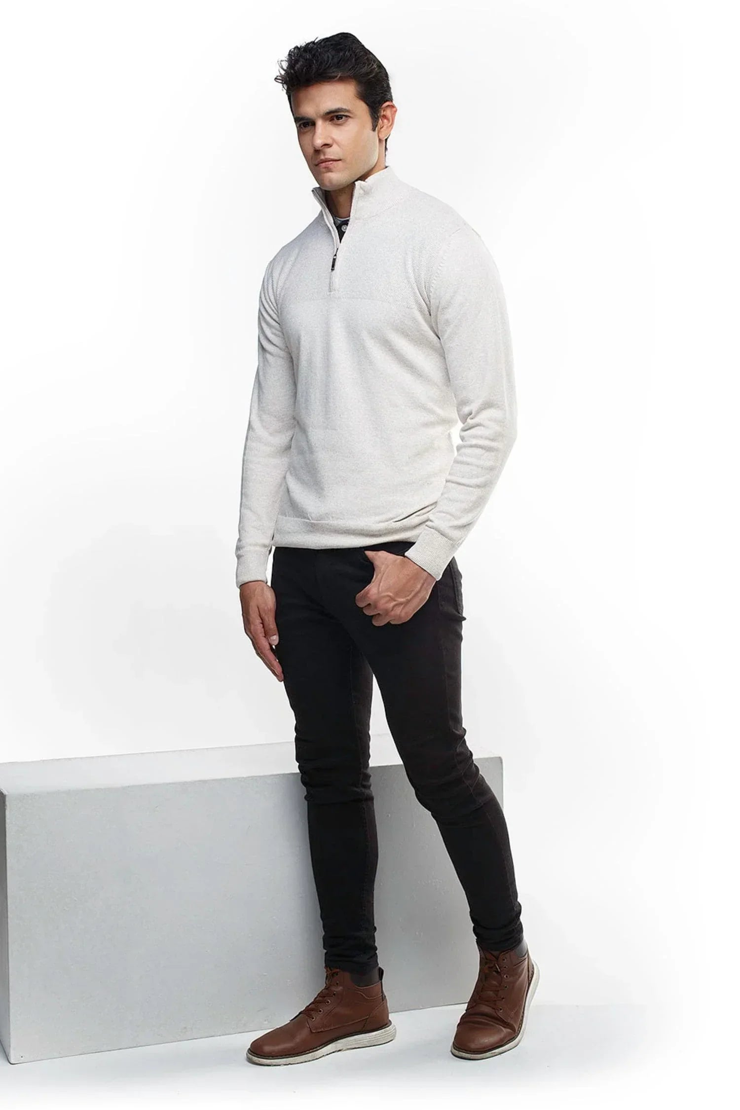 Hombre con suéter tejido beige de cremallera, pantalón negro y botines marrones